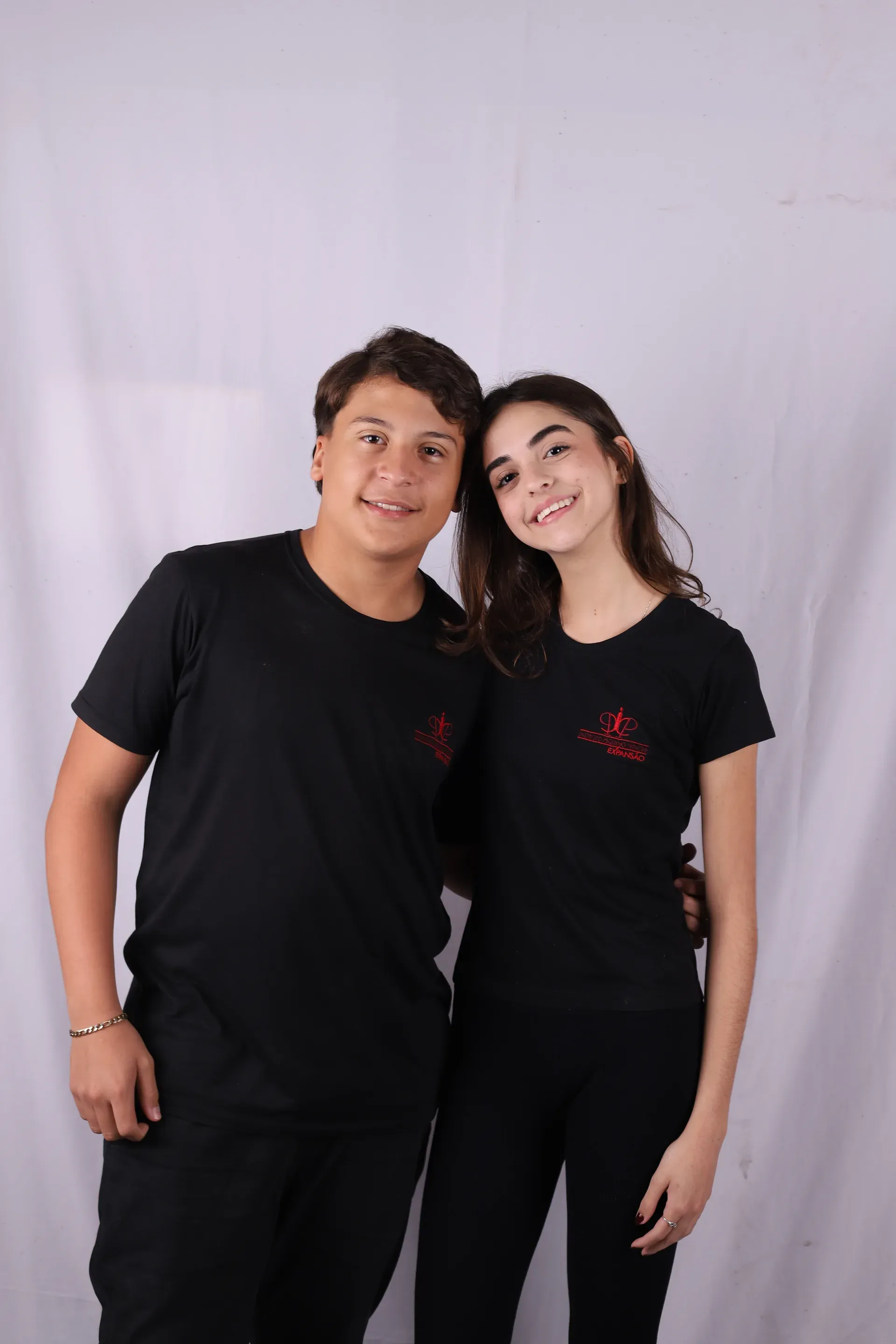 Dois colegas do Fundamental II abraçados e sorrindo, de camiseta preta do IPP