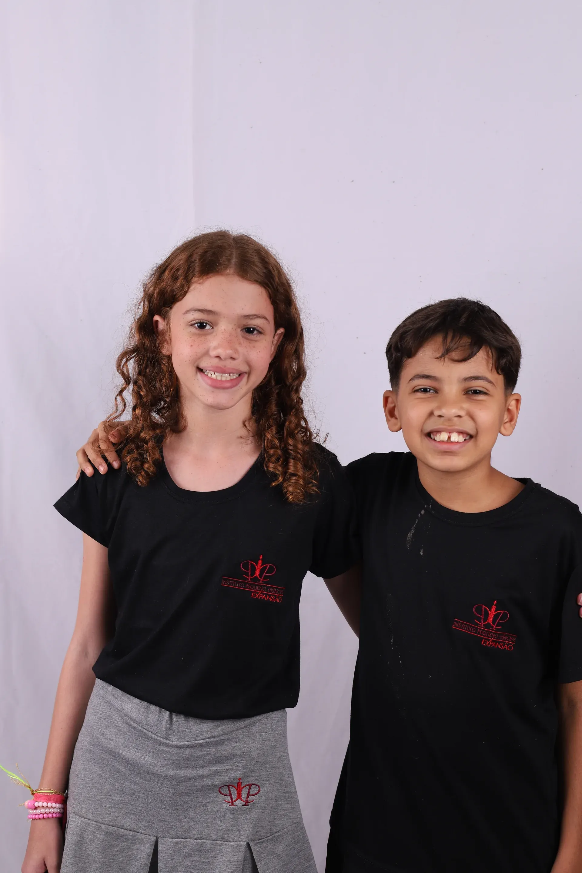 Dupla de alunos do Fundamental I sorrindo, abraçados, de camiseta do IPP