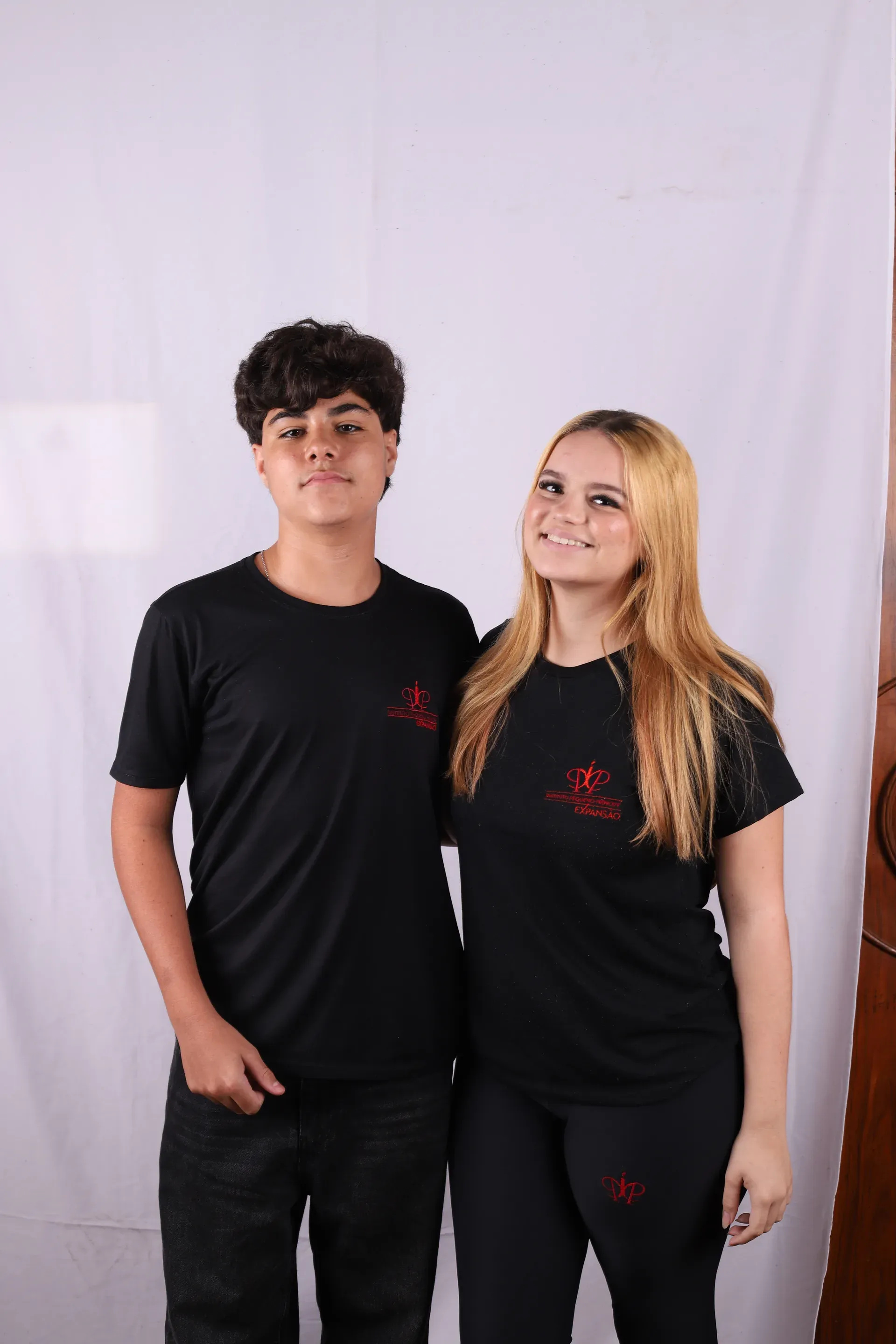 Dupla de colegas do Ensino Médio lado a lado, de camiseta do IPP